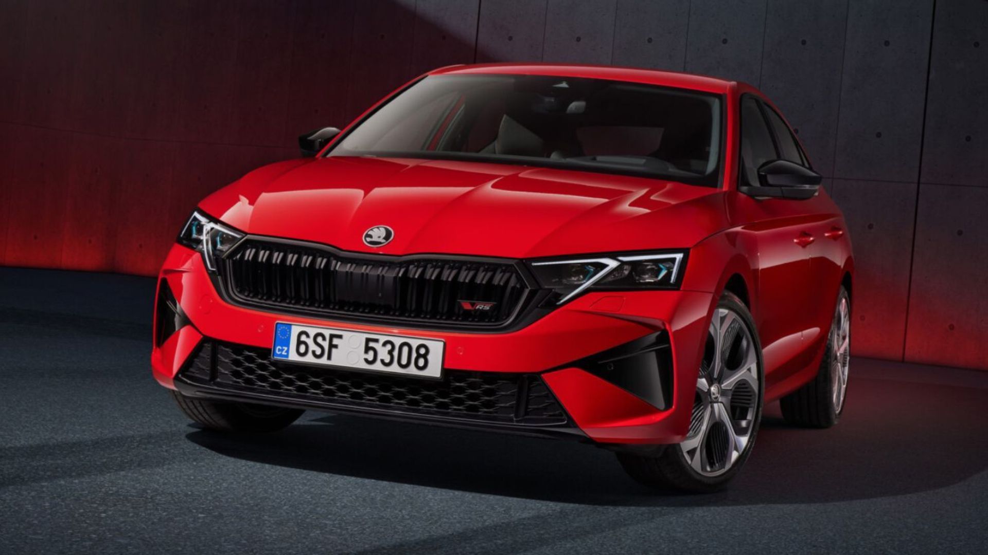 New Skoda Octavia RS 2025 front view in bright red, showcasing sporty design, black grille, and RS badge.
